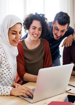A multi-ethnic group of young friends with laptop indoors, house sharing concept.